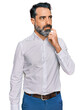Middle aged man with beard wearing casual white shirt serious face thinking about question with hand on chin, thoughtful about confusing idea