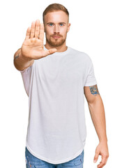 Wall Mural - Young irish man wearing casual clothes doing stop sing with palm of the hand. warning expression with negative and serious gesture on the face.