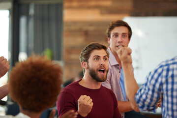 Sticker - It pays to be a winner. Shot of a group of designers looking excited during an informal meeting.