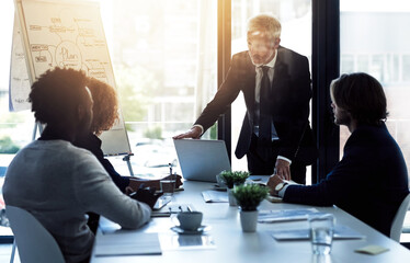 Poster - Strategizing in the boardroom. Shot of a mature businessman giving a presentation to colleagues in a boardroom.