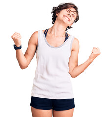 Canvas Print - Beautiful young woman with short hair wearing casual sport clothes very happy and excited doing winner gesture with arms raised, smiling and screaming for success. celebration concept.