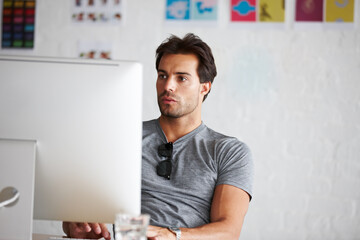 Poster - Doing work online. A handsome young man sitting in front of his computer.