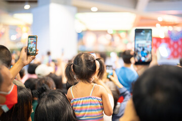 Crowd, group of young people kid, cheering in live music concert in front of colorful stage lights in school. Children event