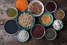 Different Legumes (lentils, Beans, Chickpeas, Mung, Peas) In Bowls And Plates On Wooden Background.