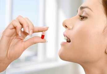 Wall Mural - Dietary supplement concept, young woman accepts medical pill.