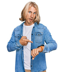 Poster - Caucasian man with blond long hair wearing casual denim jacket in hurry pointing to watch time, impatience, upset and angry for deadline delay