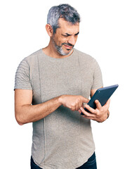 Canvas Print - Middle age hispanic with grey hair using touchpad device clueless and confused expression. doubt concept.