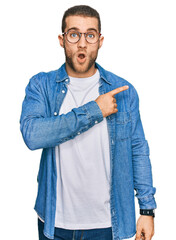 Canvas Print - Young caucasian man wearing casual clothes surprised pointing with finger to the side, open mouth amazed expression.