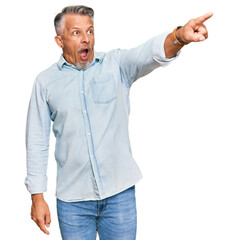 Canvas Print - Middle age grey-haired man wearing casual clothes pointing with finger surprised ahead, open mouth amazed expression, something on the front