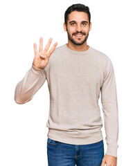 Wall Mural - Young hispanic man wearing casual clothes showing and pointing up with fingers number four while smiling confident and happy.