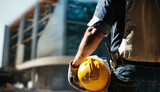 Fototapeta  - Construction worker holding his helmet while looking at construction site. Occupational Safety and Health (OSH) 
