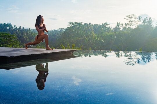 good morning with yoga meditating on sunrise background. active woman in bikini practicing at villa 