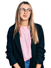 Wall Mural - Hispanic young woman wearing business jacket and glasses smiling looking to the side and staring away thinking.