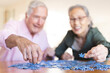 © Wavebreak Media - Happy senior diverse couple sitting at table and doing puzzles