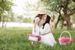© Andriy Medvediuk - Mothers Day, Womens day. Young beautiful mother is spending time with little daughter in the green summer park. Mom with child are holding baskets of peonies flowers together on nature. Family look