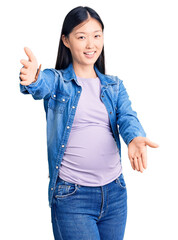 Wall Mural - Young beautiful chinese woman pregnant expecting baby looking at the camera smiling with open arms for hug. cheerful expression embracing happiness.