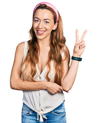 Poster - Young caucasian woman wearing casual style with sleeveless shirt smiling with happy face winking at the camera doing victory sign with fingers. number two.