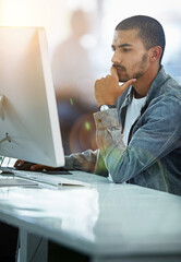 Poster - He always gives his work one hundred percent focus. Shot of a young designer deep in thought while working on a computer in a modern office.