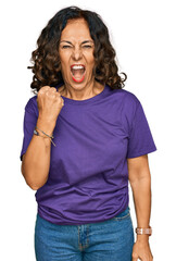 Poster - Middle age hispanic woman wearing casual clothes angry and mad raising fist frustrated and furious while shouting with anger. rage and aggressive concept.