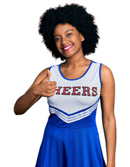 Canvas Print - Young african american woman wearing cheerleader uniform doing happy thumbs up gesture with hand. approving expression looking at the camera showing success.