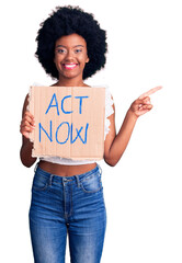 Canvas Print - Young african american woman holding act now banner smiling happy pointing with hand and finger to the side