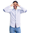© Krakenimages.com - Handsome hispanic man wearing business shirt and glasses doing ok gesture like binoculars sticking tongue out, eyes looking through fingers. crazy expression.