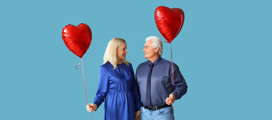 Wall Mural - Happy mature couple with heart shaped balloons on blue background