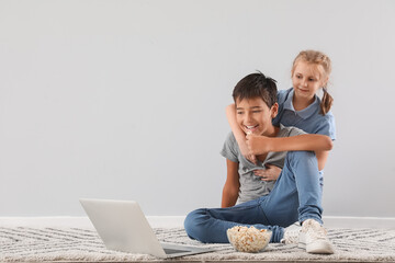 Poster - Little boy and his sister watching cartoons on laptop near light wall