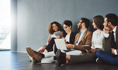 Aufkleber - Teamwork makes great work. Studio shot of a group of businesspeople using wireless technology and talking on the floor against a gray wall.