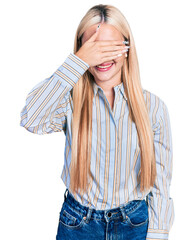 Wall Mural - Beautiful blonde woman wearing casual striped shirt smiling and laughing with hand on face covering eyes for surprise. blind concept.