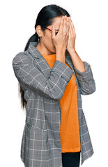 Wall Mural - Young hispanic girl wearing business jacket and glasses with sad expression covering face with hands while crying. depression concept.