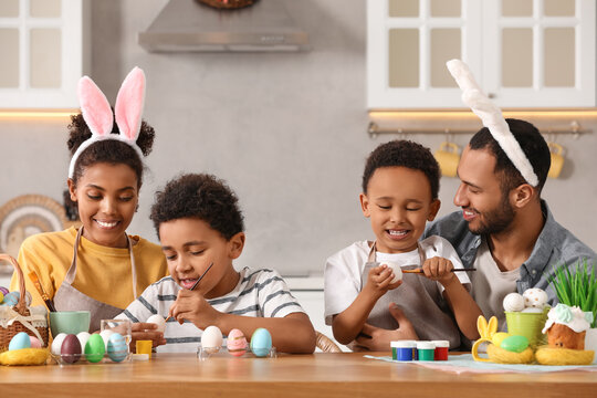 Wall Mural - Happy African American family painting Easter eggs at table in kitchen