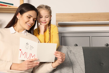 Wall Mural - Happy woman receiving greeting card from her little daughter at home