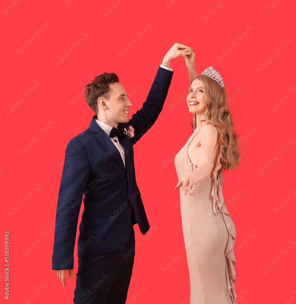 Beautiful couple dressed for prom dancing on red background