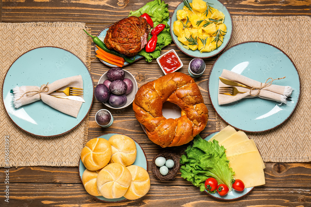 Tasty dishes and painted eggs for Easter dinner on wooden background