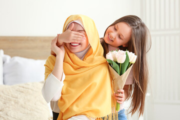 Poster - Little girl with tulips closing her Muslim mother's eyes in bedroom