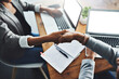 © Delmaine D/peopleimages.com - Partnering up was the best decision. High angle shot of two businesswomen shaking hands in an office.