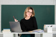 © Volodymyr - Portrait of female beautiful teacher teaching high school students with computer laptop in classroom on blackboard.