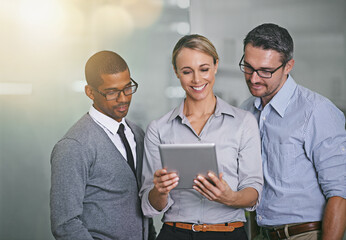 Canvas Print - The secret to business success. Cropped shot of three businesspeople working on a digital tablet.