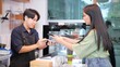 Asian woman customer and barista using smartphone to scan QR code tag on another smartphone in a coffee shop or restaurant to accepted generate digital pay without money