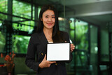 Fototapeta  - Portrait of confident asian businesswoman showing digital tablet. White empty screen for advertising or text message.