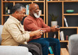 © Malik E/peopleimages.com - Gaming, fun and senior black man friends playing a video game together in the living room of a home. Sofa, funny or retirement with a mature male gamer and friend enjoying a house visit to game