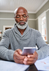 Poster - Now you can bank from anywhere. Cropped shot of a senior man using his cellphone while working on his finances at home.
