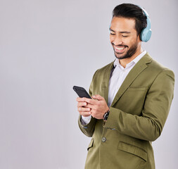 Poster - Asian man, phone and smile in social media with headphones for communication against a gray studio background. Happy formal male smiling on smartphone with headset listening to music on mockup