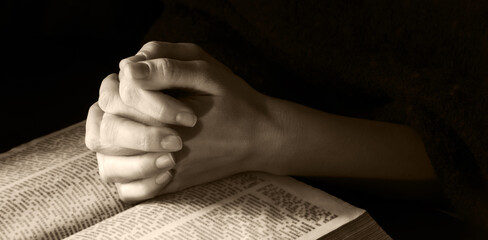 Wall Mural - Hands clasped in prayer near an open book