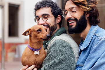 portrait of a happy little dog in the arms of its owners, concept of family lifestyle with pets and 