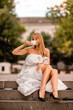 © svetograph - Woman city blanket. Morning in the big city. A blonde woman in a white blanket is enjoying a cup of tea in the city center.