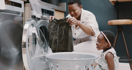 Wall Mural - Laundry, mother and child helping with folding of clothes together in a house. Happy, excited and young girl giving help to her mom while cleaning clothing from a washing machine in their home