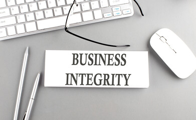 BUSINESS INTEGRITY text on paper with keyboard on grey background