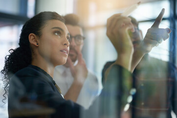 Fototapete - Succeeding is top priority. Shot of a group of colleagues brainstorming together on a glass wall in an office.